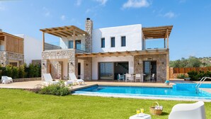 Una casa moderna de dos pisos con piscina, mobiliario exterior y fachada de piedra.