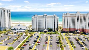Ein Hotel mit mehreren Hochhäusern, einem Parkplatz und Blick auf den Strand.