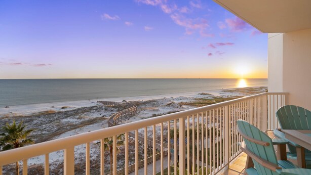 Ein Balkon mit Blick auf den Strand und das Meer bei Sonnenuntergang.