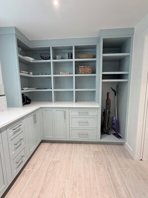 A kitchen with light blue cabinets, a white countertop, and a built-in shelving unit.