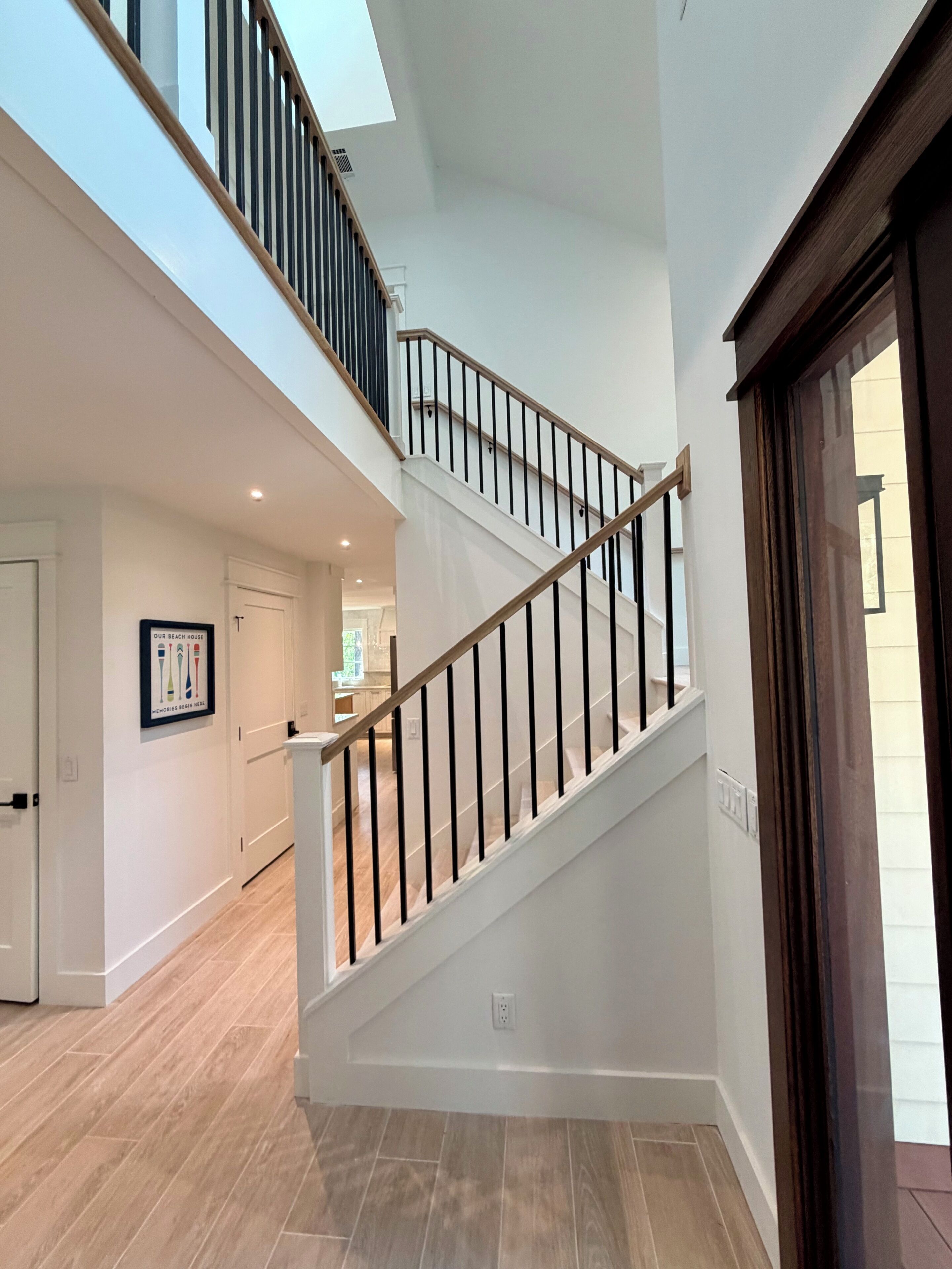 Espacio interior de varios niveles con una escalera, piso de madera y vista hacia una cocina.