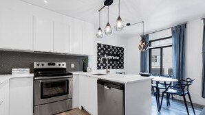 Een moderne keuken met roestvrijstalen apparatuur, een centraal eiland en een eethoek met een tafel en stoelen.