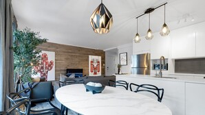 Een moderne keuken met witte kasten, een roestvrijstalen afzuigkap en hanglampen.
