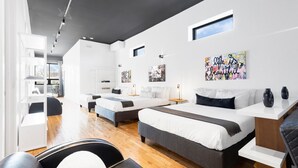 A modern hotel room with three beds, a dining area, and artwork on the walls. - LiV MTL Plaza Grand Luxe Penthouse Near Downtown Montreal (Montréal)
