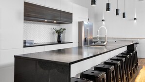A modern kitchen with a large island, bar stools, and pendant lighting. - LiV MTL Plaza Grand Luxe Penthouse Near Downtown Montreal (Montréal)
