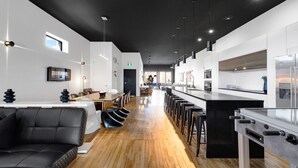 A modern kitchen with a long counter, bar stools, and a central island. - LiV MTL Plaza Grand Luxe Penthouse Near Downtown Montreal (Montréal)