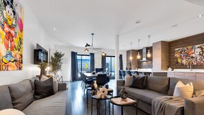 Un salon moderne comprenant un ensemble de canapés, un coin repas et une cuisine.