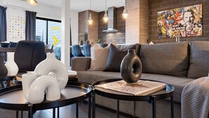 Un salon moderne avec un canapé gris, une décoration en noir et blanc et une grande œuvre d’art accrochée au mur.