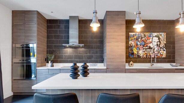 Une cuisine moderne dotée d’un grand îlot central, d’appareils électroménagers en acier inoxydable et d’une fresque murale.