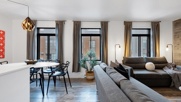 Ein modernes Wohnzimmer mit einer Couch, einem Esstisch mit Stühlen und einer Topfpflanze.