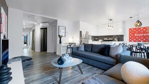 Ein modernes Wohnzimmer mit einem grauen Sofa, einem Couchtisch und einem Essbereich mit roter Wand und einem Louis Vuitton Schild.