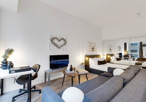 A modern hotel room with a sofa, a TV, a desk, and a bed.