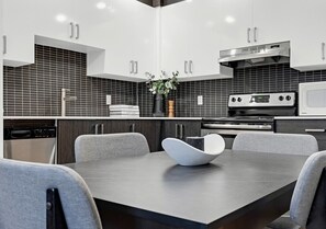 A modern kitchen with dark tiled backsplash, stainless steel appliances, and a central island with a white bowl.