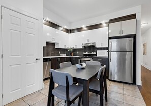 Una cocina moderna con una mesa de comedor, sillas y un refrigerador de acero inoxidable.