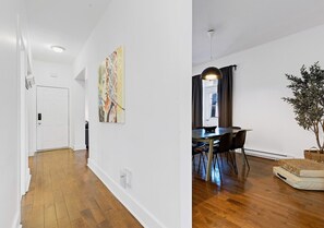 A hallway with a door, a dining area with a table and chairs, and a plant. - Spacious 4BR rooftop near Downtown (Montréal)