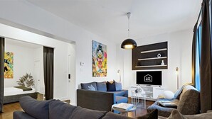 A modern living room with a sofa, a coffee table, a TV, and a bookshelf. - Spacious 4BR rooftop near Downtown (Montréal)