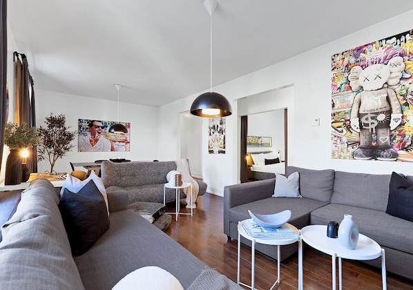 A modern living room with grey sofas, a round coffee table, and a pendant light.