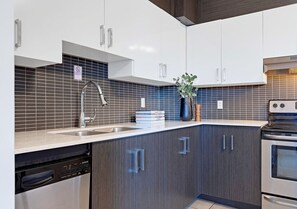 Una cocina moderna con lavavajillas, estufa y una planta en la encimera.