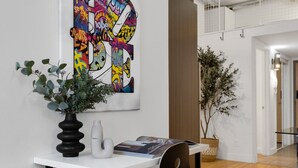 Un intérieur moderne avec une table blanche, un tableau abstrait aux couleurs vives et deux plantes en pot.