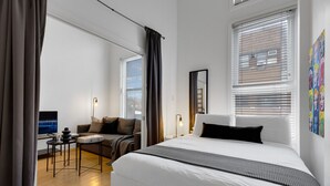 Une chambre d’hôtel moderne équipée d’un grand lit, d’un bureau avec un ordinateur, d’un canapé et d’une télévision.