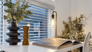 A modern room with a white table, a book, a vase with plants, and a lamp. - LiV MTL Main Plateau Urban Suites Near Downtown Montreal (Montréal)