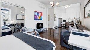 A modern apartment with a living room, dining area, and kitchenette. There is a bed, a TV, and a large window. - LiV MTL MTL Plateau Urban Suites Near Downtown Montreal (Montréal)
