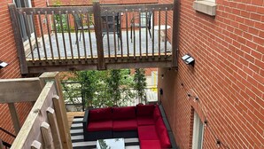 A rooftop patio with a red sectional sofa, a black and white striped rug, and a wooden deck railing. - LiV MTL MTL Plateau Urban Suites Near Downtown Montreal (Montréal)