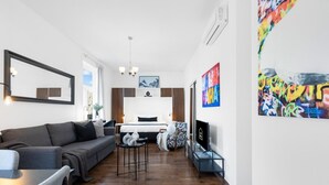 A modern living room with a sofa, a small table, and a bed in the background. - LiV MTL MTL Plateau Urban Suites Near Downtown Montreal (Montréal)