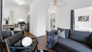 A modern apartment with a dining area, kitchenette, and a living room with a gray sofa and a painting on the wall. - LiV MTL MTL Plateau Urban Suites Near Downtown Montreal (Montréal)