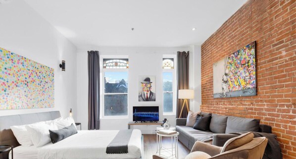 Una habitación de hotel moderna con cama, sofá, televisor y obras de arte en las paredes.