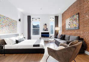 A modern hotel room with a large bed, a sofa, a coffee table, and a TV. - Downtown-302 Spacious Downtown Double Studio • Sleeps 4 (Montréal)