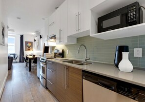 A modern kitchen with stainless steel appliances, a dishwasher, and a microwave. - Spacious Downtown 2BR • Sleeps 6 (Montréal)