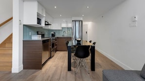 Une cuisine moderne avec un coin repas, un plancher en bois et des murs blancs.