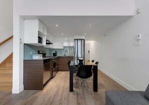 Eine moderne Küche mit Essbereich, Holzboden und weißen Wänden.