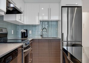 A modern kitchen with stainless steel appliances, a dishwasher, and a double sink. - Downtown Duplex Mezzanine • Sleeps 8 (Montréal)