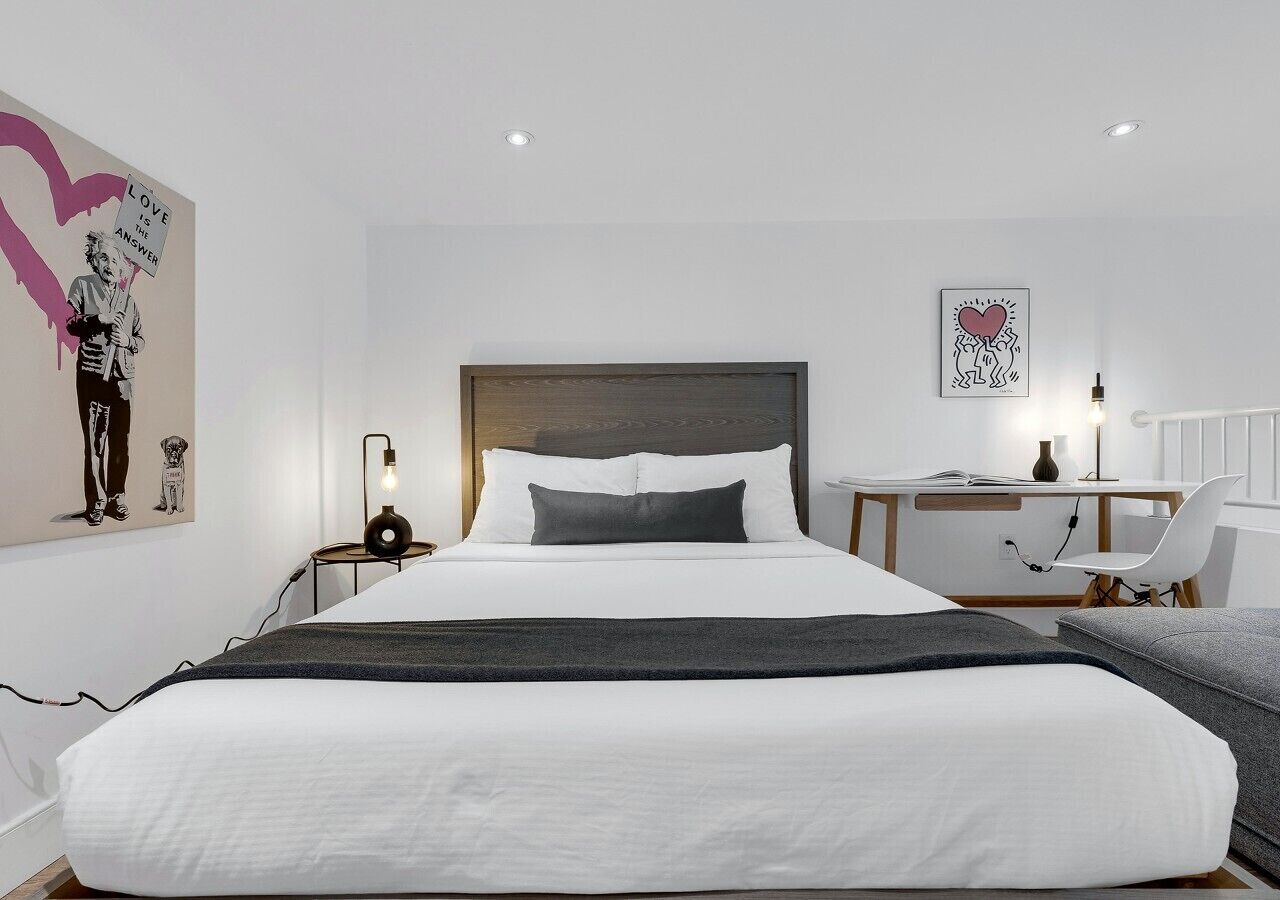 A modern hotel room with a large bed, a desk, and a chair.