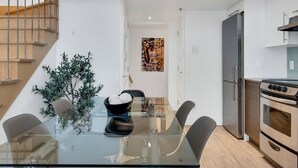 Eine moderne Küche mit einem Edelstahl-Kühlschrank, einem eingebauten Backofen und einem Glastisch mit Stühlen.