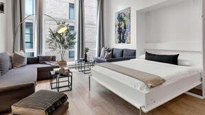 Ein modernes Schlafzimmer mit einem großen Bett, einem Sofa, einem kleinen Tisch und einer Zimmerpflanze.