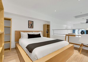 Une chambre moderne avec un grand lit, des étagères intégrées, un bureau et un ventilateur de plafond.