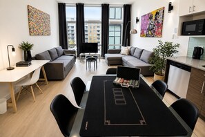 Un salon moderne comprenant une table à manger, des canapés, un téléviseur et un coin cuisine.