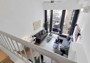 Un salón moderno con sofá, mesa de centro y vistas a la ciudad a través de grandes ventanales.