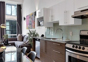 A modern kitchen with white cabinets, a built-in oven, and a stainless steel range hood.