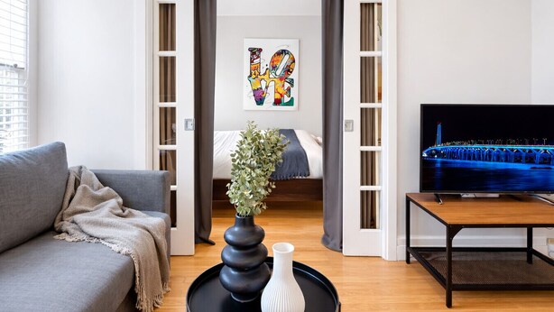 Un soggiorno moderno con divano, tavolino, televisore e un letto con vista su un ponte.