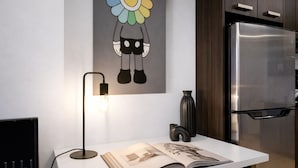 Una cucina moderna con frigorifero in acciaio inossidabile, una luce a parete e un quadro decorativo con dei fiori.