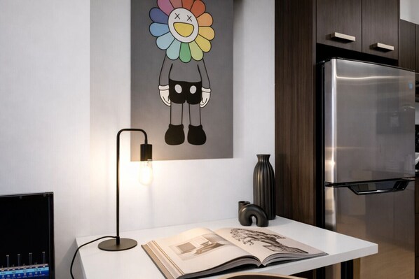 Een moderne keuken met een roestvrijstalen koelkast, een wandlamp en een decoratief bloemschilderij.