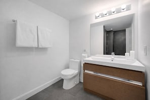 Un baño moderno con inodoro, lavamanos, espejo y toallero.