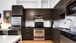 Una cucina moderna con mobili in legno scuro, elettrodomestici in acciaio inossidabile e un piano di lavoro bianco.