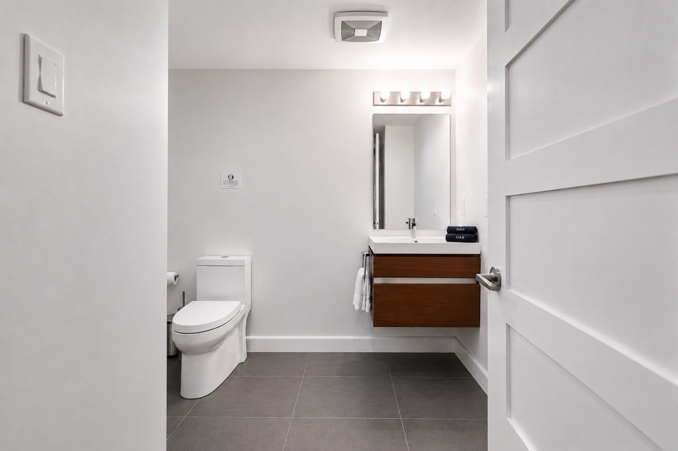 A modern bathroom with a toilet, sink, and mirror.
