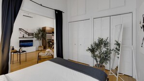 Une chambre d’hôtel moderne équipée d’un grand lit, d’un bureau, d’une chaise, d’une plante en pot et d’une armoire.
