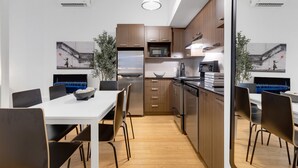 Une cuisine moderne avec des meubles en bois, un réfrigérateur en acier inoxydable et un four à micro-ondes. On y trouve une table à manger avec des chaises et un canapé bleu.